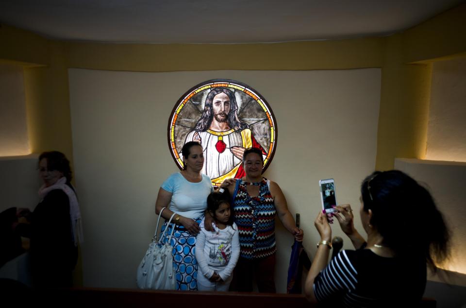 Parishioners pose for a photo backdropped by a stained glass window inside the newly consecrated Sagrado Corazon de Jesus Catholic church or Sacred Heart, in Sandino, Cuba, Saturday, Jan. 26, 2019. Of the three Catholic churches the Cuban government has authorized, the Sacred Heart of Jesus church is the first in 60 years to be completed. It was finished with the help of Tampa's St. Lawrence Catholic Church in Florida. (AP Photo/Ramon Espinosa)