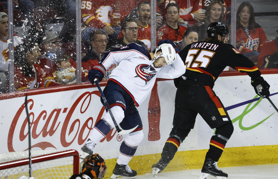 Columbus Blue Jackets forward Cole Sillinger (4) is checked by Calgary Flames defenseman Noah Hanifin (55) during the second period of an NHL hockey game Thursday, Jan. 25, 2024, in Calgary, Alberta. (Jeff McIntosh/The Canadian Press via AP)