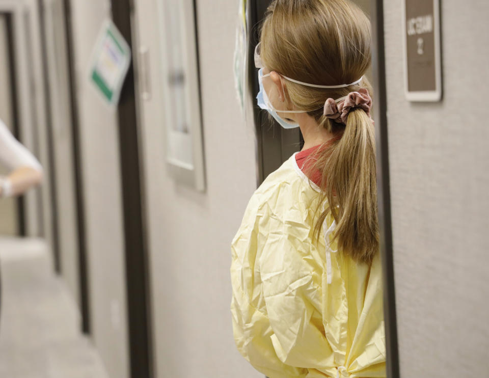 Physician assistant Nicole Thomas steps out of an exam room to ask for more test items at Primary Health Medical Group's clinic in Boise, Idaho, Tuesday, Nov. 24, 2020. Troops direct people outside the urgent-care clinic revamped into a facility for coronavirus patients as infections and deaths surge in Idaho and nationwide. Some 1,000 people have died due to COVID-19, and infections this week surpassed 100,000. (AP Photo/Otto Kitsinger)