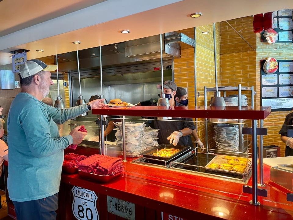 A passenger grabs his burger from Guy's Burger Joint on the Carnival Vista.