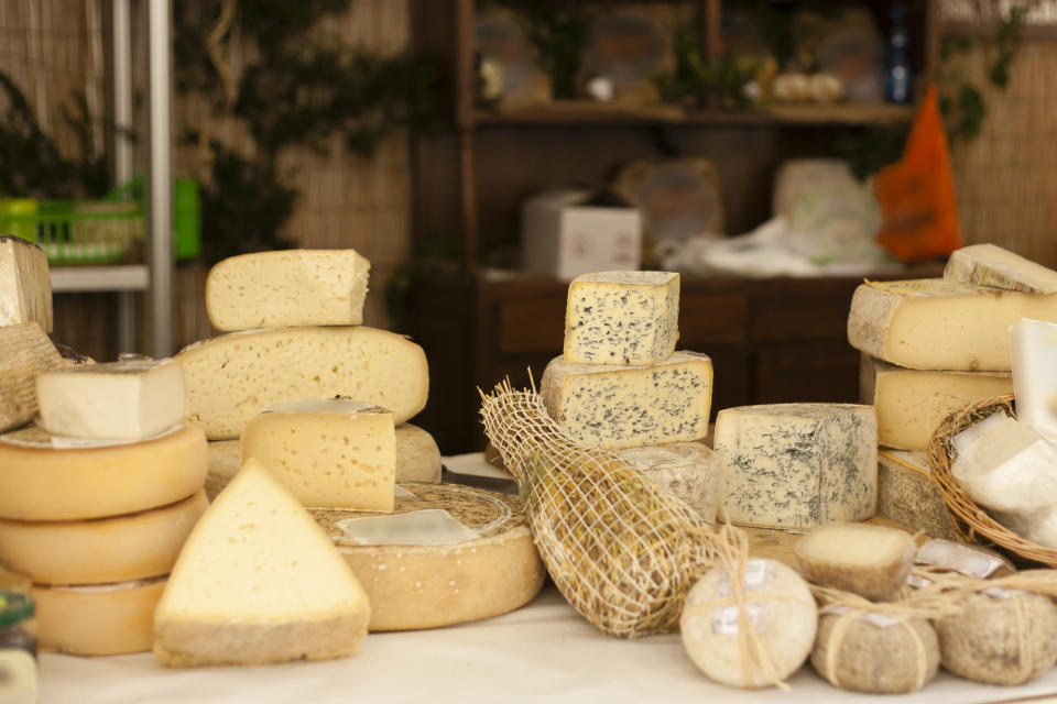 Slices of different cheese, neatly arranged on a market stall.