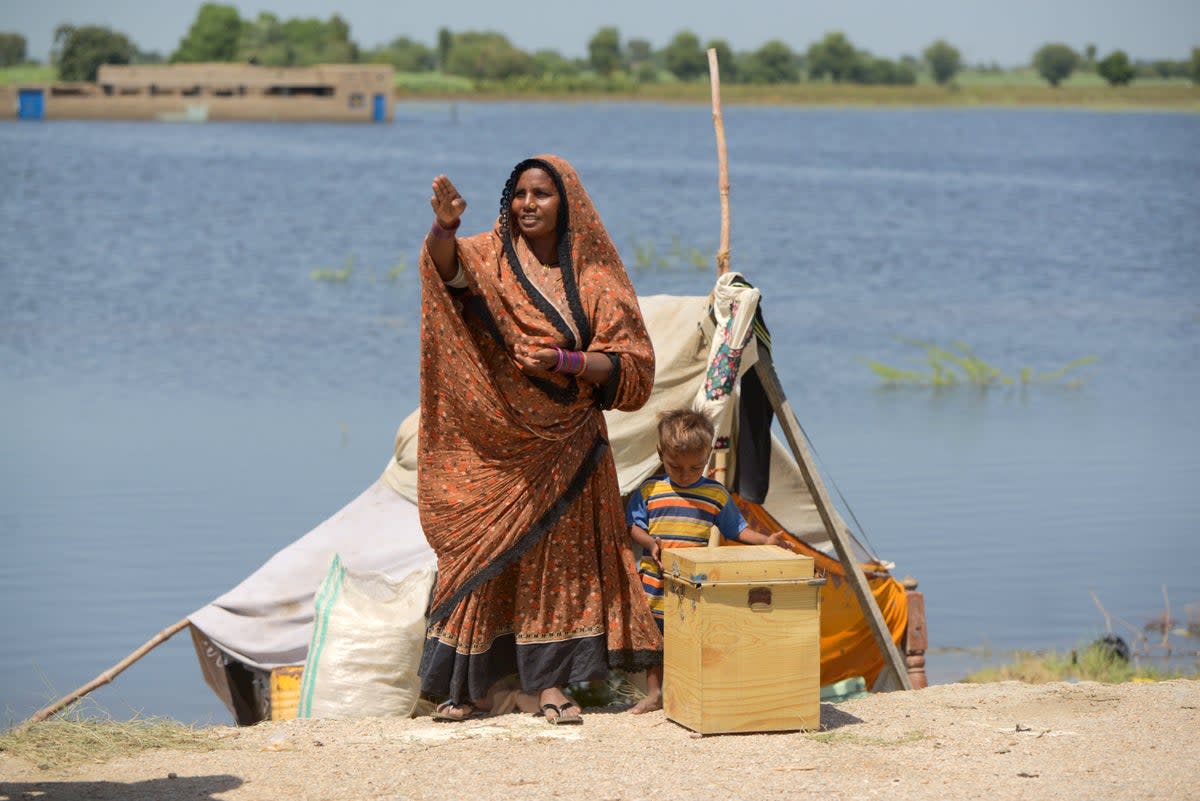 Soni, 37, stands with her family in front of her temporary shelter in Sindh (Akifullah Khan/DEC)