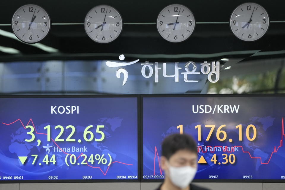 A currency trader walks by the screens showing the Korea Composite Stock Price Index (KOSPI), left, and the foreign exchange rate between U.S. dollar and South Korean won at a foreign exchange dealing room in Seoul, South Korea, Friday, Sept. 17, 2021. Asian shares were mixed on Friday after a hodge-podge of economic data led Wall Street to close mostly lower. (AP Photo/Lee Jin-man)