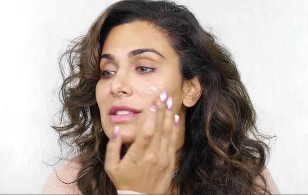 Huda Kattan starts off by applying lubricant to her face. Photo: YouTube/Huda Kattan