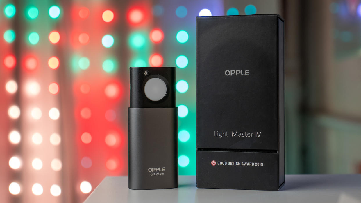  The Opple Light Master 4 next to its box with Christmas lights in the background. 