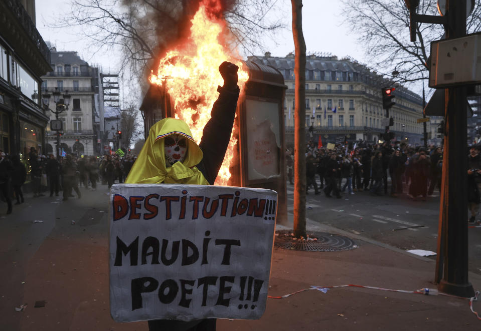 A protester holds a placard that reads, "destitution of the cursed poet " during a rally in Paris, Thursday, march 23, 2023. French unions are holding their first mass demonstrations Thursday since President Emmanuel Macron enflamed public anger by forcing a higher retirement age through parliament without a vote. (AP Photo/Aurelien Morissard)