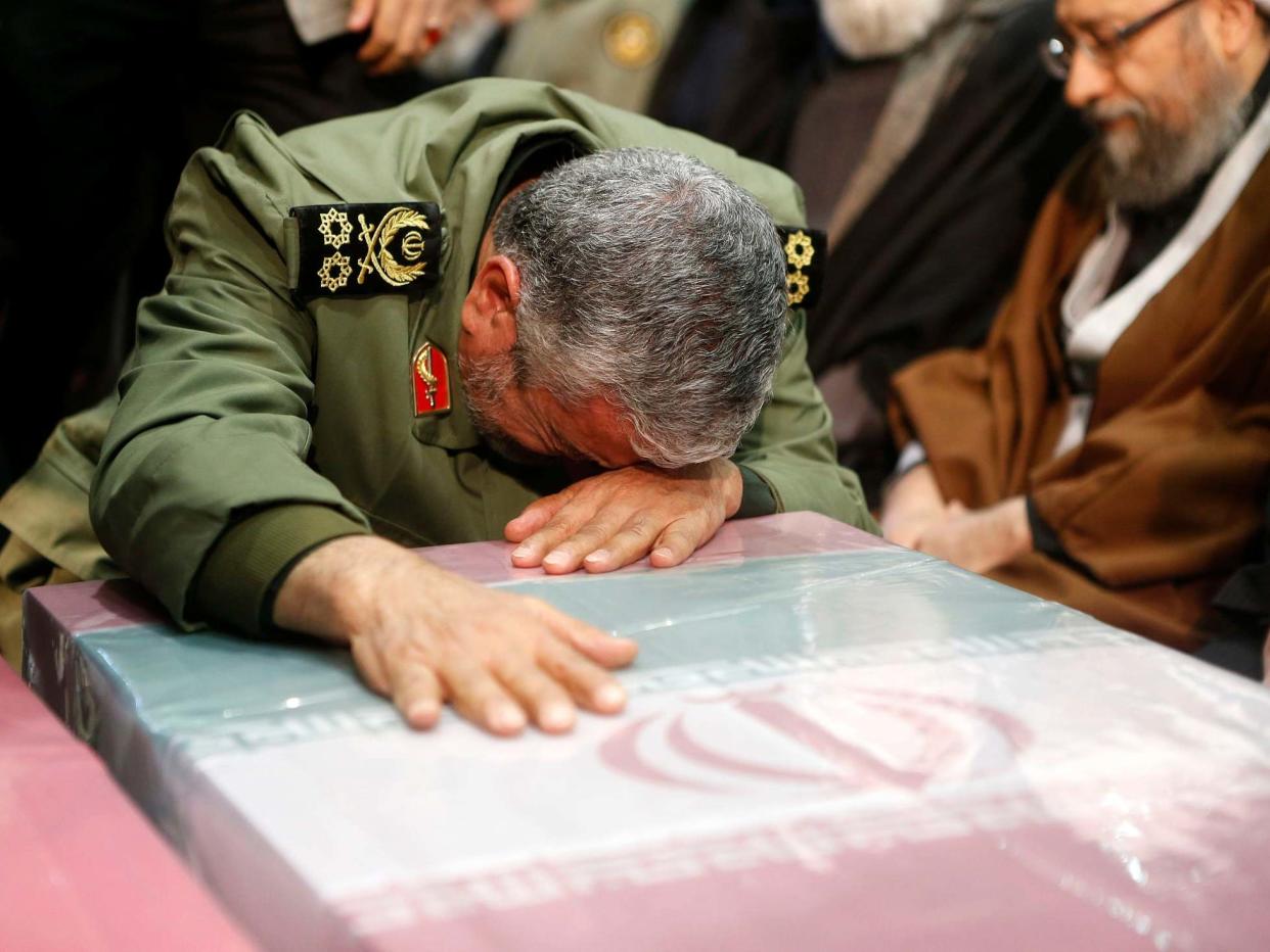 A Revolutionary Guard commander prays over the caskets of slain Iranian military commander Qasem Soleimani during a funeral ceremony in Tehran: IRANIAN SUPREME LEADER'S WEBSITE