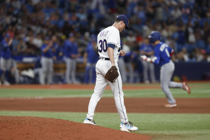 Tampa Bay Rays relief pitcher Brooks Raley walks off the mound after giving up a three-run home run to Toronto Blue Jays' Whit Merrifield, behind, during the seventh inning of a baseball game Saturday, Sept. 24, 2022, in St. Petersburg, Fla. (AP Photo/Scott Audette)