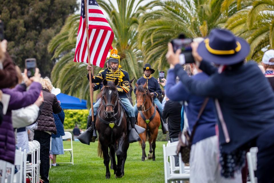 Mounted Buffalo Soldiers deliver the presentation of colors, before the start of a Memorial Day ceremony