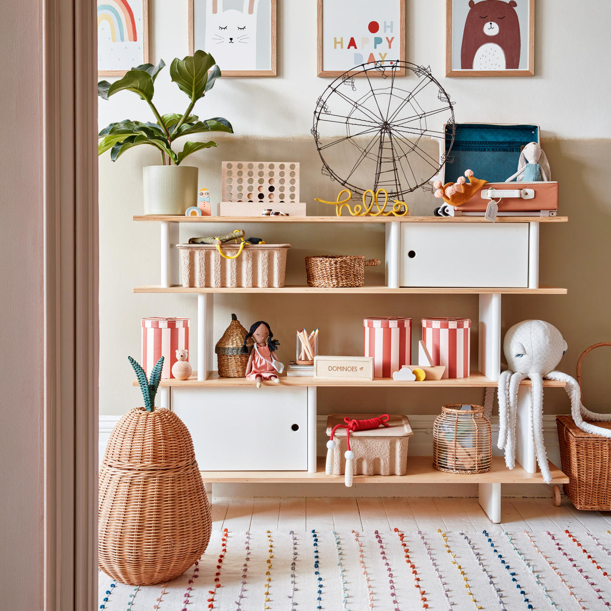  Pink and white open shelving unit in a kids' room, with baskets for organising. 