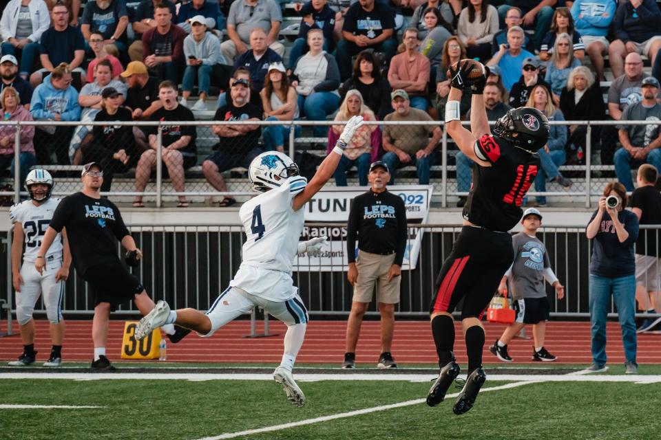 New Philadelphia's Owen Schoelles makes a leaping catch as Louisville's Ty Paumier can't make the block, Friday, Aug. 18 at Woody Hayes Quaker Stadium in New Philadelphia.