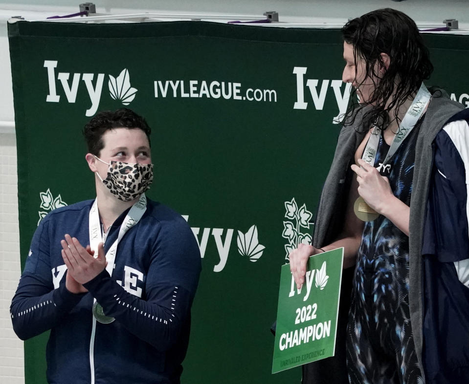 Yale's Iszak Henig, left, applauds Pennsylvania's Lia Thomas, right, after Thomas won the 100-yard freestyle final and Henig finished second at the Ivy League women's swimming and diving championships at Harvard University, Saturday, Feb. 19, 2022, in Cambridge, Mass. Henig, who is transitioning to male but has not begun hormone treatments yet, is swimming for the Yale women's team and Thomas, who is transitioning to female, is swimming for the Penn women's team. (AP Photo/Mary Schwalm)