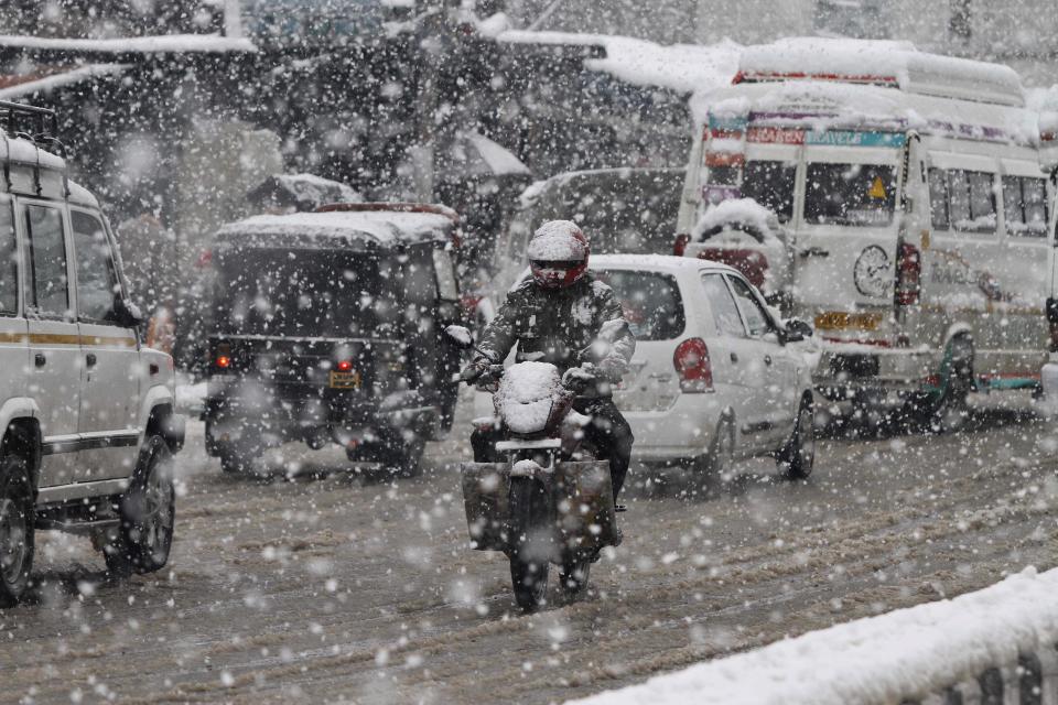 A man rides a motorcycle as it snows in Srinagar, India, Tuesday, March 11, 2014. The Kashmir valley was Tuesday cut off from rest of India due to heavy snowfall. (AP Photo/Mukhtar Khan)