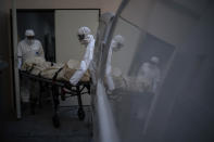 Mortuary workers pick up the body of a COVID-19 victim from a nursing home in Barcelona, Spain, Thursday, Nov. 19, 2020. After successfully bringing the daily death count down from over 900 in March to single digits by July, Spain has seen a steady uptick that brought deaths back to over 200 a day this month. With that relapse, the body collectors have returned to making the rounds of hospitals, homes and care facilities. (AP Photo/Emilio Morenatti)