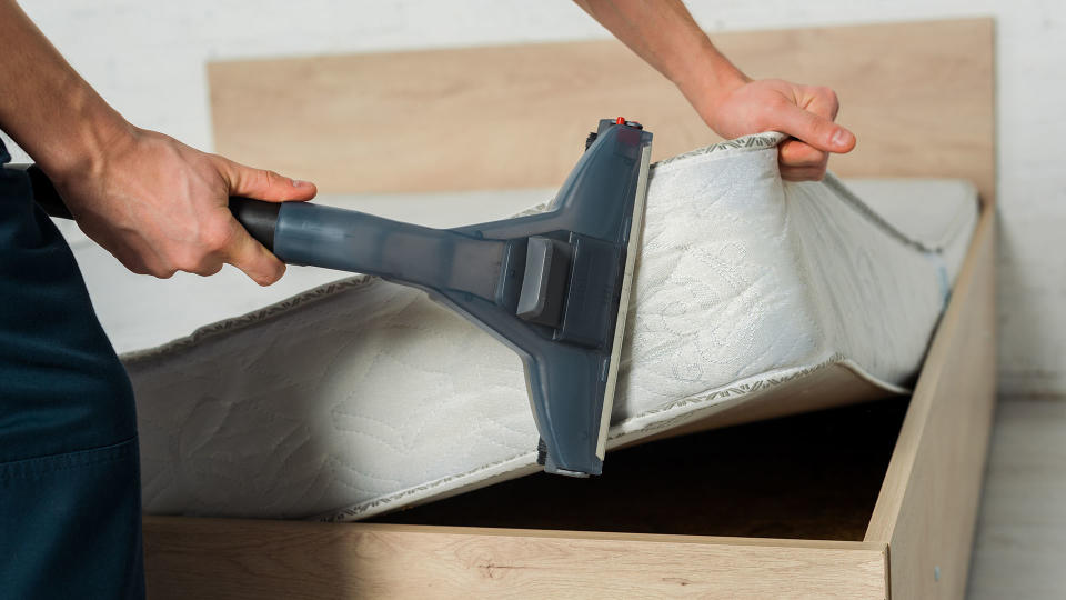 Person hoovers the side of a mattress