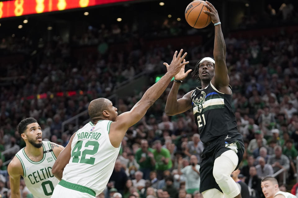 Boston Celtics forward Jayson Tatum (0) and center Al Horford (42) defend as Milwaukee Bucks guard Jrue Holiday (21) drives toward the basket during the first half of Game 7 of an NBA basketball Eastern Conference semifinals playoff series, Sunday, May 15, 2022, in Boston. (AP Photo/Steven Senne)