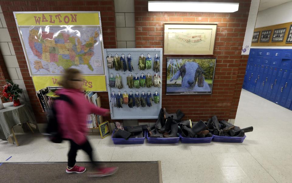 In this Thursday, Dec. 12, 2013 photo, a student walks past a supply of work gloves and boots worn to do chores at the Walton 21st Century Rural Life Center in Walton, Kan. Located in a small farming community, the school faced closing before re-establishing itself as an agriculture-focused charter school and more than doubling enrollment. (AP Photo/Charlie Riedel)