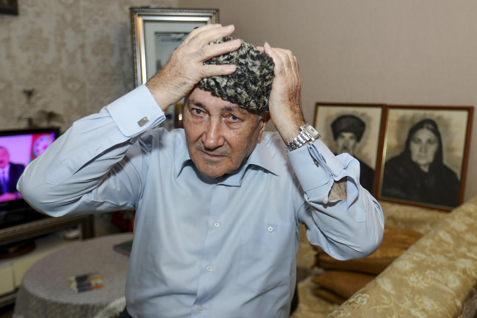 Velyeddin Ismayilov, 77, an Azerbaijani refugee from Kalbajar region puts on a national hat prior to his interview with the Associated Press in Baku, Azerbaijan, Wednesday, Nov. 25, 2020. Ismayilov says he fled Kalbajar with his wife and three young children, and his big house is now ruined. But he is prepared to return and restore his home town, and build a new house for his family. "With my grown-up children, grandchildren we will build an even better house," he said. (AP Photo/Aziz Karimov)