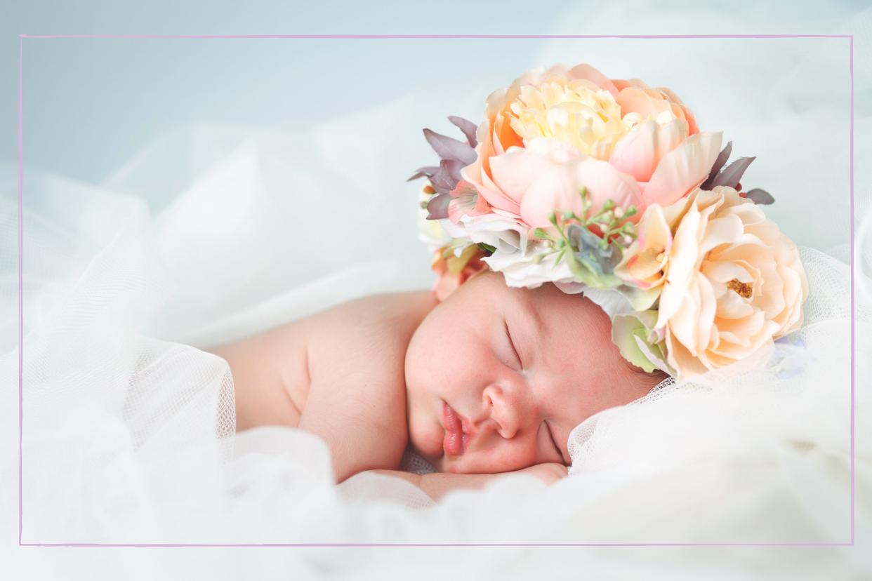  A sleeping baby with flowers on its head. 