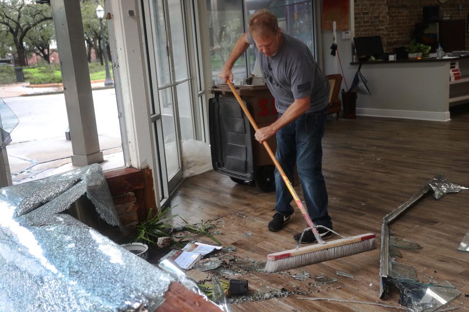 Morgan Griffin cleans up the broken window in the store he works in as Hurricane Sally passes through Mobile, Alabama.