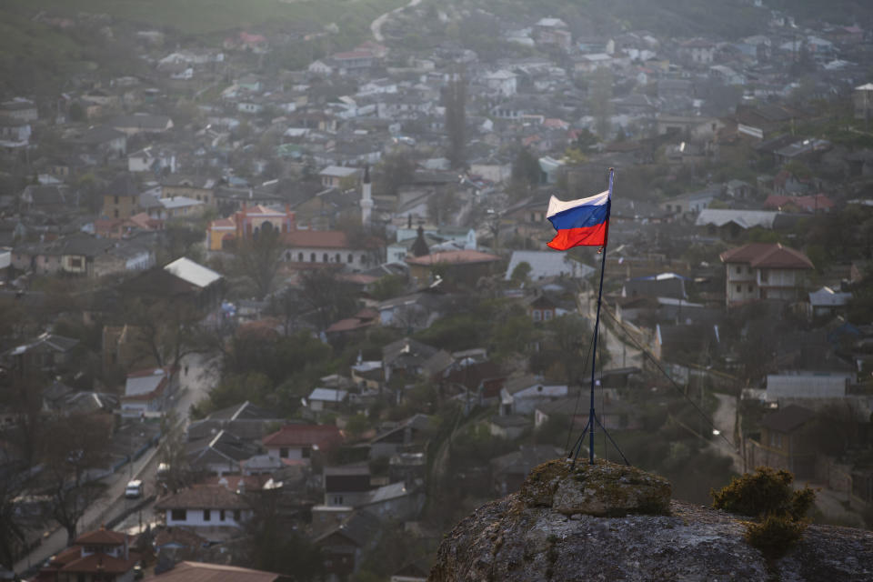 FILE - In this March 28, 2014 file photo, a Russian national flag flies on a hilltop near the city of Bakhchysarai, Crimea. Russia's annexation of the Crimea region of Ukraine in March 2014 marked the climax of President Vladimir Putin's quest to restore Moscow's influence over its neighbors and reverse decades of perceived humiliation at the hands of the West. (AP Photo/Pavel Golovkin, File