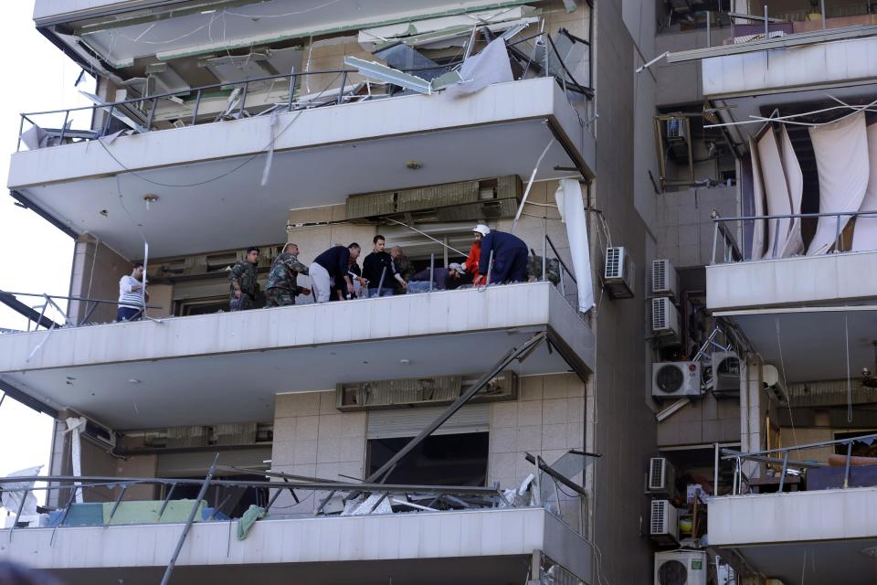 Lebanese soldiers and citizens help wounded people at the site of an explosion near the Kuwaiti Embassy and Iran's cultural center, in the suburb of Beir Hassan, Beirut, Lebanon, Wednesday, Feb. 19, 2014. (AP Photo/Hassan Ammar)