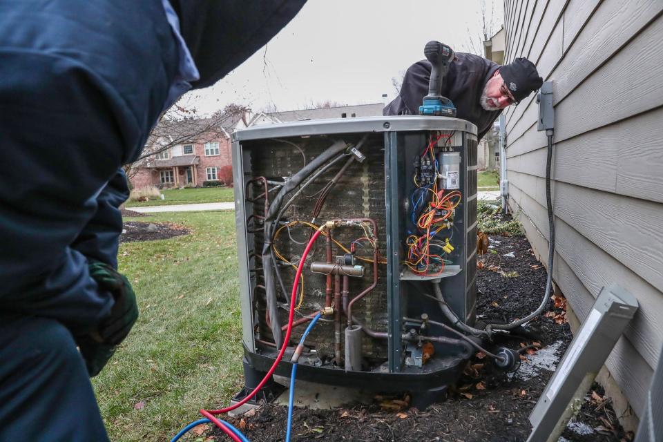 HVAC technicians do some work on a heat pump at a home in Fishers, Ind. As electricity bills and emissions continue to go up, homeowners are exploring electric heat pumps as a way to heat and cool their homes and help the environment and their wallets.