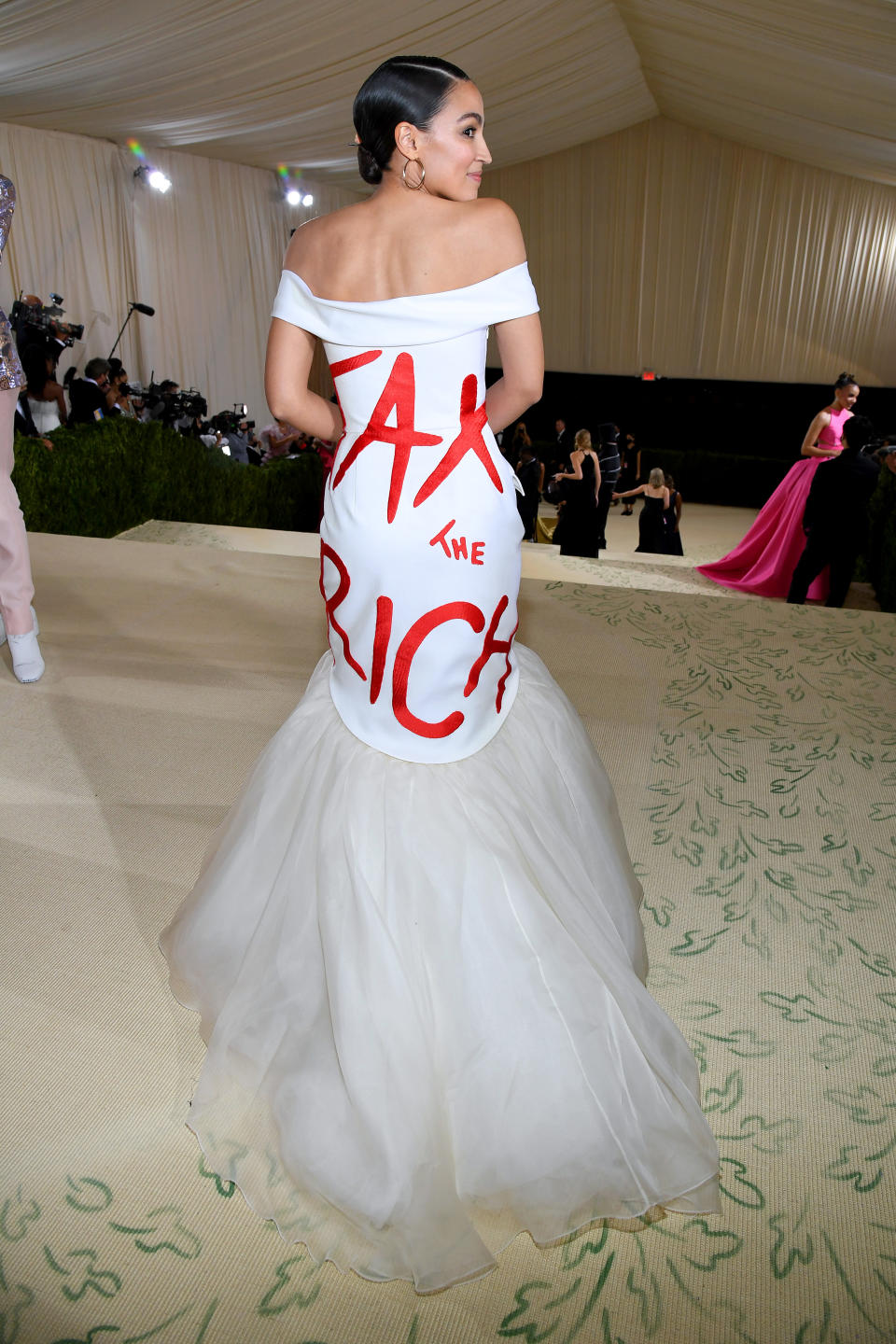 <p>Alexandria Ocasio-Cortez a fait polémique sur le tapis rouge du Met Gala. Sa robe blanche, simple en apparence, portait un message en grosses lettres rouges : "Taxons les riches". Ce cri de ralliement contre les grosses fortunes qui continuent à prospérer alors que les plans d'aide aux personnes plus modestes mettent beaucoup de temps à se mettre en place n'est pas nouveau pour la femme politique. Le slogan avait d'ailleurs été repris par Joe Biden pendant sa campagne présidentielle, mais le résultat n'a pas fait plaisir aux Républicains. (Photo by Kevin Mazur/MG21/Getty Images For The Met Museum/Vogue)</p> 