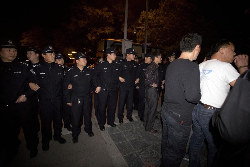 Chinese police men lock arms to prevent relatives of Chinese passengers onboard the Malaysia Airlines MH370 from marching to the Malaysian embassy from a hotel in Beijing, China, Thursday, April 24, 2014. Angry relatives who had been waiting for more than 8 hours in vain for a Malaysia embassy representative to attend their daily meetings marched to the Malaysia embassy and protested through the night. (AP Photo/Ng Han Guan)