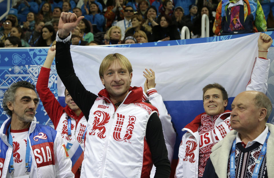 Evgeny Plyushchenko of Russia, centre, gestures after receiving his results in the men's team short program figure skating competition at the Iceberg Skating Palace during the 2014 Winter Olympics, Thursday, Feb. 6, 2014, in Sochi, Russia. (AP Photo/Darron Cummings, Pool)