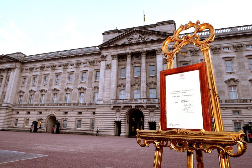 The birth announcement is displayed on an easel in front of Buckingham Palace.