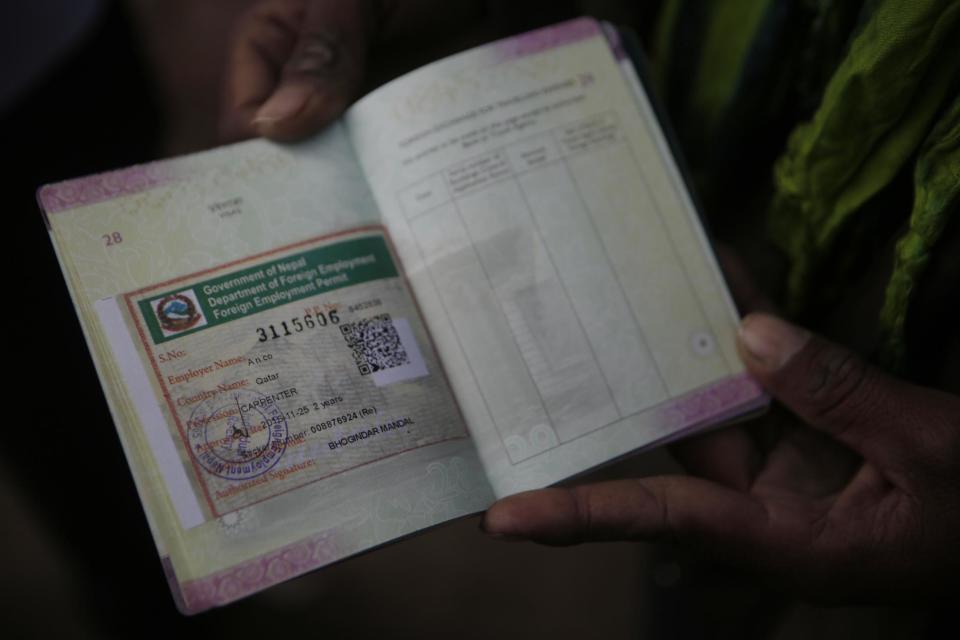 In this Nov 25, 2016 photo, a Nepalese man shows his passport with a working permit at the Department of Foreign Employment (DoFE) in Kathmandu, Nepal. The number of Nepali workers going abroad has more than doubled since the country began promoting foreign labor in recent years: from about 220,000 in 2008 to about 500,000 in 2015. The unskilled workers fill a host of global demands: building highways, stadiums and houses in Gulf states and guarding shopping malls, sewing sweatshirts and assembling televisions in Malaysia. (AP Photo/Niranjan Shrestha)