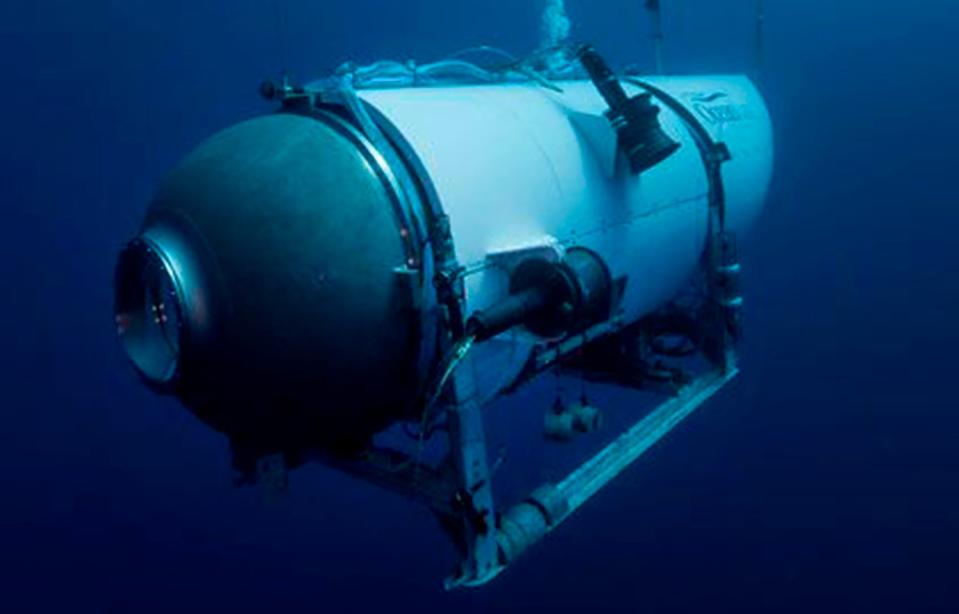 The Titan submersible, a cylindrical vessel with a small hatch at the front, diving in dark blue waters.