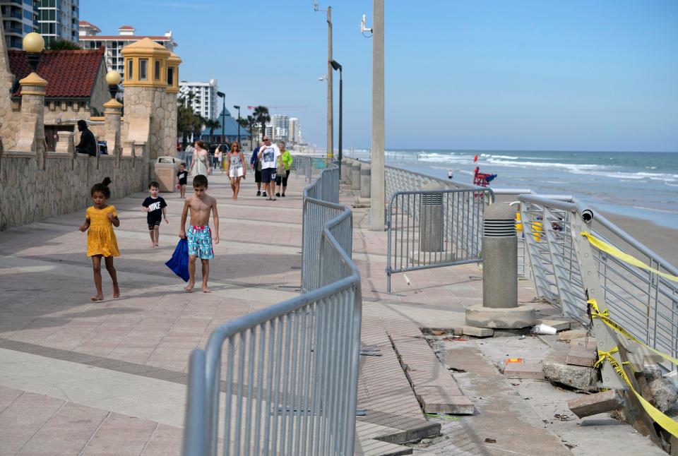 Visitors on the Daytona Beach Boardwalk stroll past barricades blocking acccess to beach stairways damaged by tropical storms Ian and Nicole. Repair of the Boardwalk involves city, county and state governments, making it a complicated process.