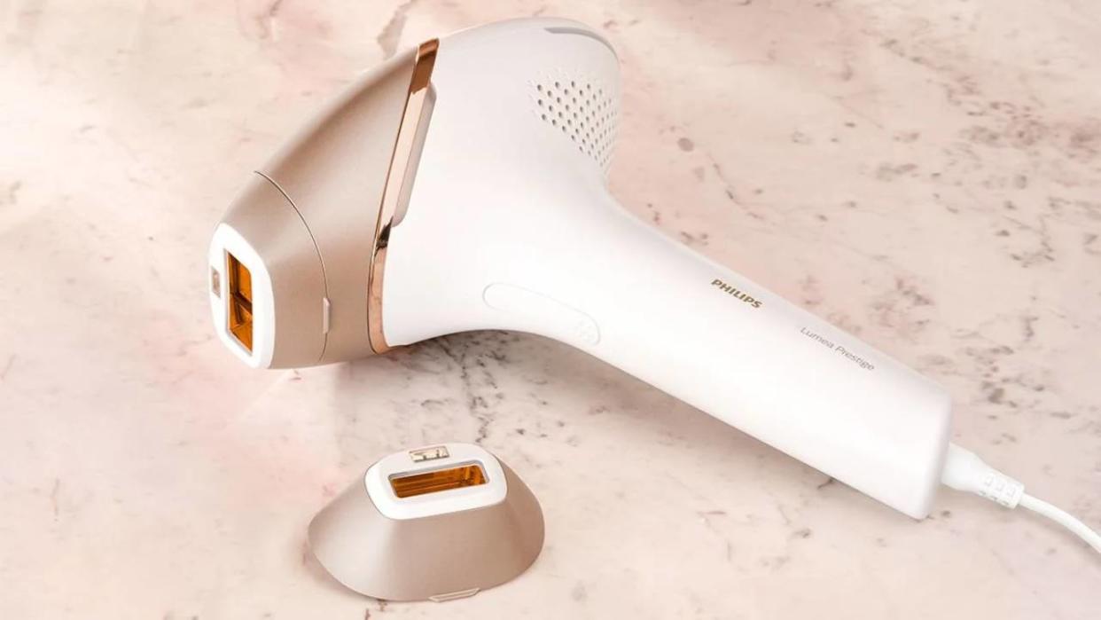  A closeup image of the Philips Lumea IPL hair removal machine lying on a counter next to its accessory. 