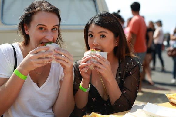 Two young women eating Shake Shack burgers at a new location opening.