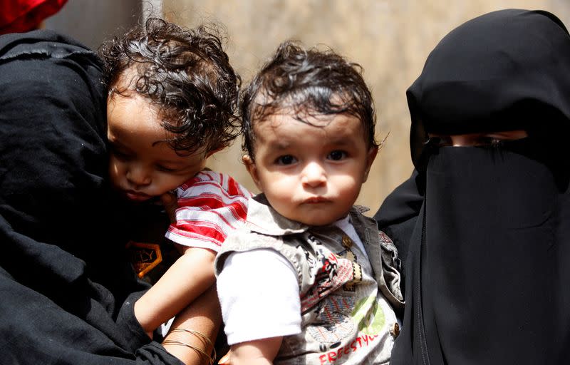 FILE PHOTO: Women hold their children as they wait outside a health center where they will receive nutritional support from the World Food Programme