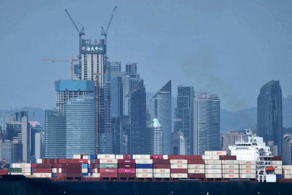 A container ship sails past the city skyline of Qingdao in eastern China's Shandong province