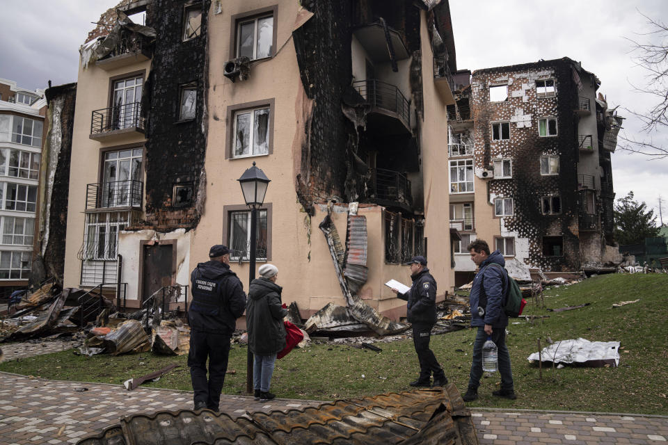 Oksana, second from left, and Yevhen, right, talk with Police officers next to their apartment building damaged by shelling in Irpin, in the outskirts of Kyiv, Ukraine, Monday, April 11, 2022. (AP Photo/Evgeniy Maloletka)