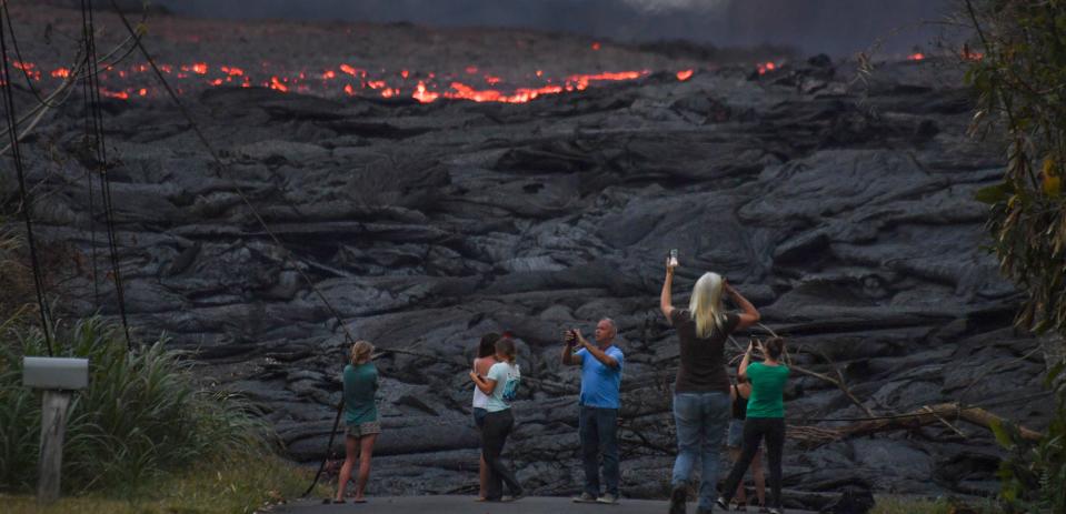 People take snapshots of lava as it pours out of cracks in the earth from the Kilauea volcano May 23, 2018, in the Leilani Estates neighborhood of Pahoa, Hawaii.