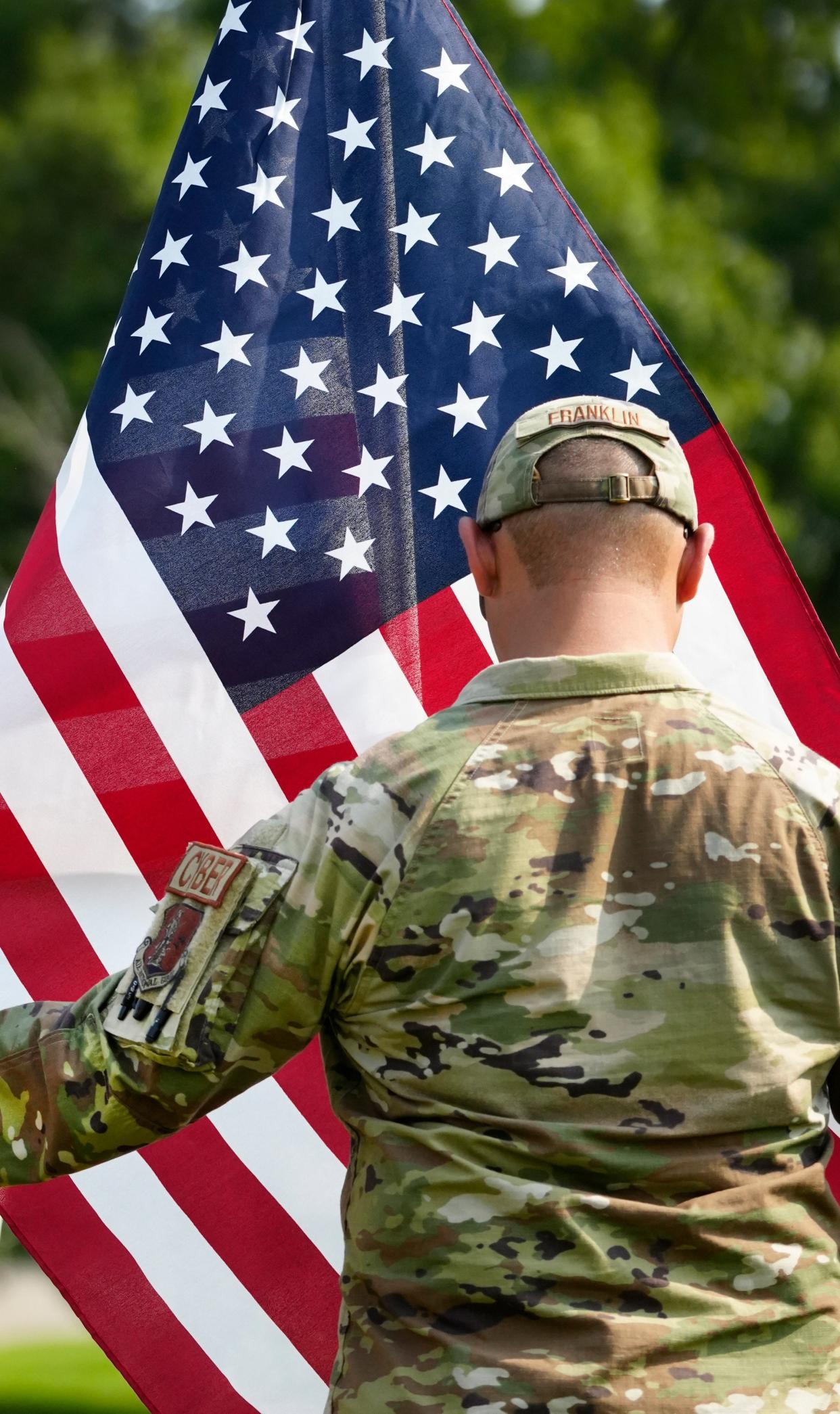 Eric Franklin, with the 123rd Air Control Squadron out of Blue Ash, unfurls one of the 1,000 flags that were installed at the Arlington Memorial Gardens in Springfield Township.