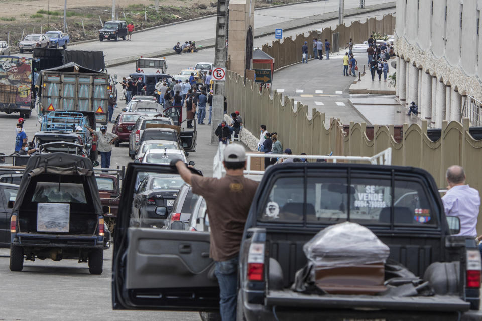 People transporting the remains of deceased loved ones wait in a slow moving line outside Jardines de la Esperanza Cemetery to hold burials in Guayaquil, Ecuador, Monday, April 6, 2020. Guayaquil, a normally bustling city that has become a hot spot in Latin America as the coronavirus pandemic spreads, also has untold numbers dying of unrelated diseases that can't be treated because hospitals are overwhelmed. (AP Photo/Luis Perez)