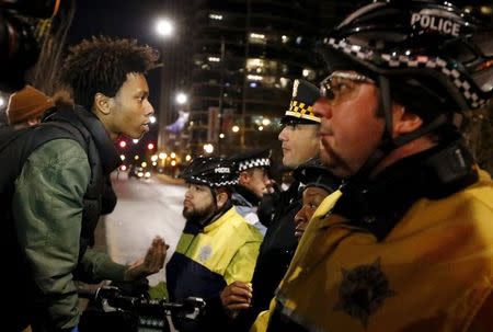 A demonstrator confronts police officers during protests in Chicago, Illinois November 24, 2015, reacting to the release of a police video of the 2014 shooting of a black teenager Laquan McDonald, by a white policeman, Jason Van Dyke. REUTERS/Jim Young