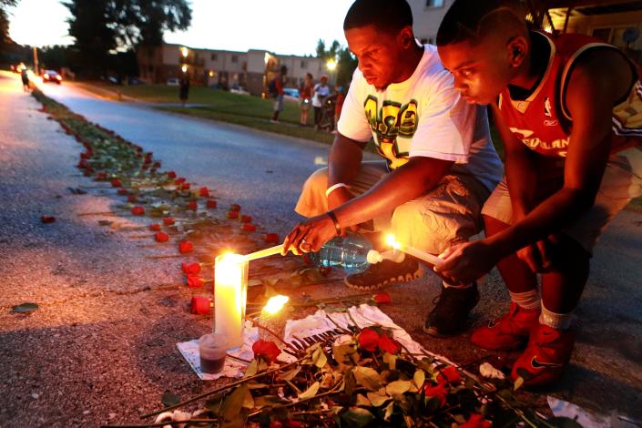 Theo Murphy, left, and his brother Jordan Marshall, 11, light candles at a memorial where unarmed Michael Brown was fatally shot by Ferguson Police Officer Darren Wilson. (AP/Post-Dispatch, Christian Gooden) 