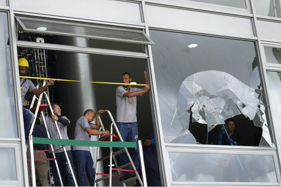 Wrokers measure the windows of Planalto Palace, the office of the president, the day after it was stormed by supporters of Brazil's former President Jair Bolsonaro in Brasilia, Brazil, Monday, Jan. 9, 2023. The protesters also stormed Congress and the Supreme Court. (AP Photo/Eraldo Peres)