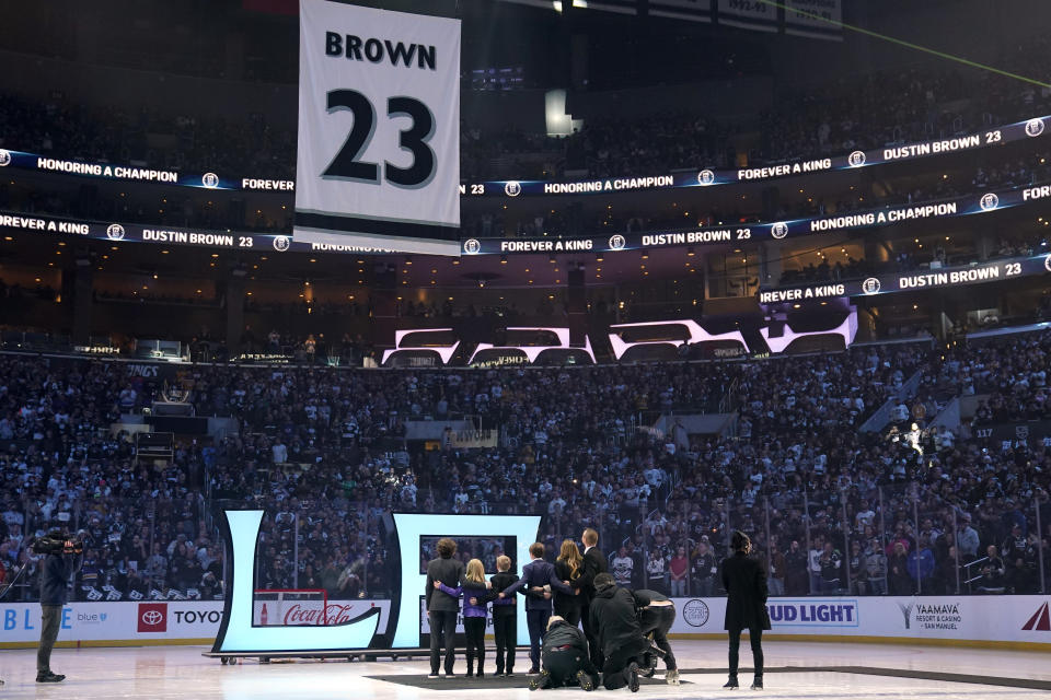 Former Los Angeles Kings right winger Dustin Brown stands with his family while his number is lifted during a ceremony to retire his jersey prior to an NHL hockey game between the Los Angeles Kings and the Pittsburgh Penguins Saturday, Feb. 11, 2023, in Los Angeles. (AP Photo/Mark J. Terrill)