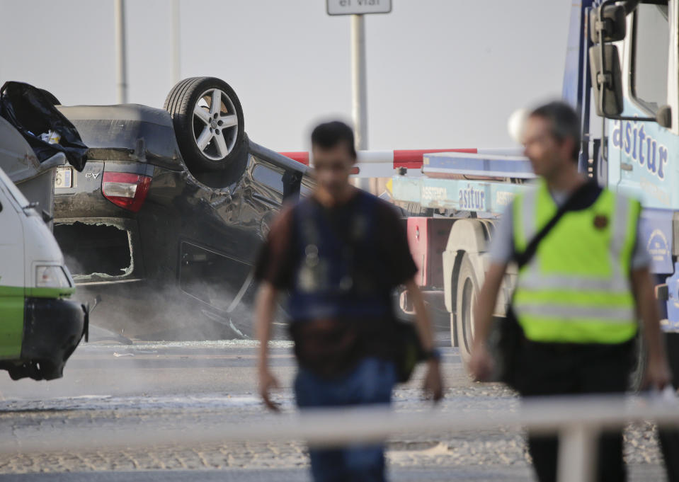 <p>Police officers walk near an overturned car onto a platform at the spot where terrorists were intercepted by police in Cambrils, Spain, Friday, Aug. 18, 2017. (Photo: Emilio Morenatti/AP) </p>