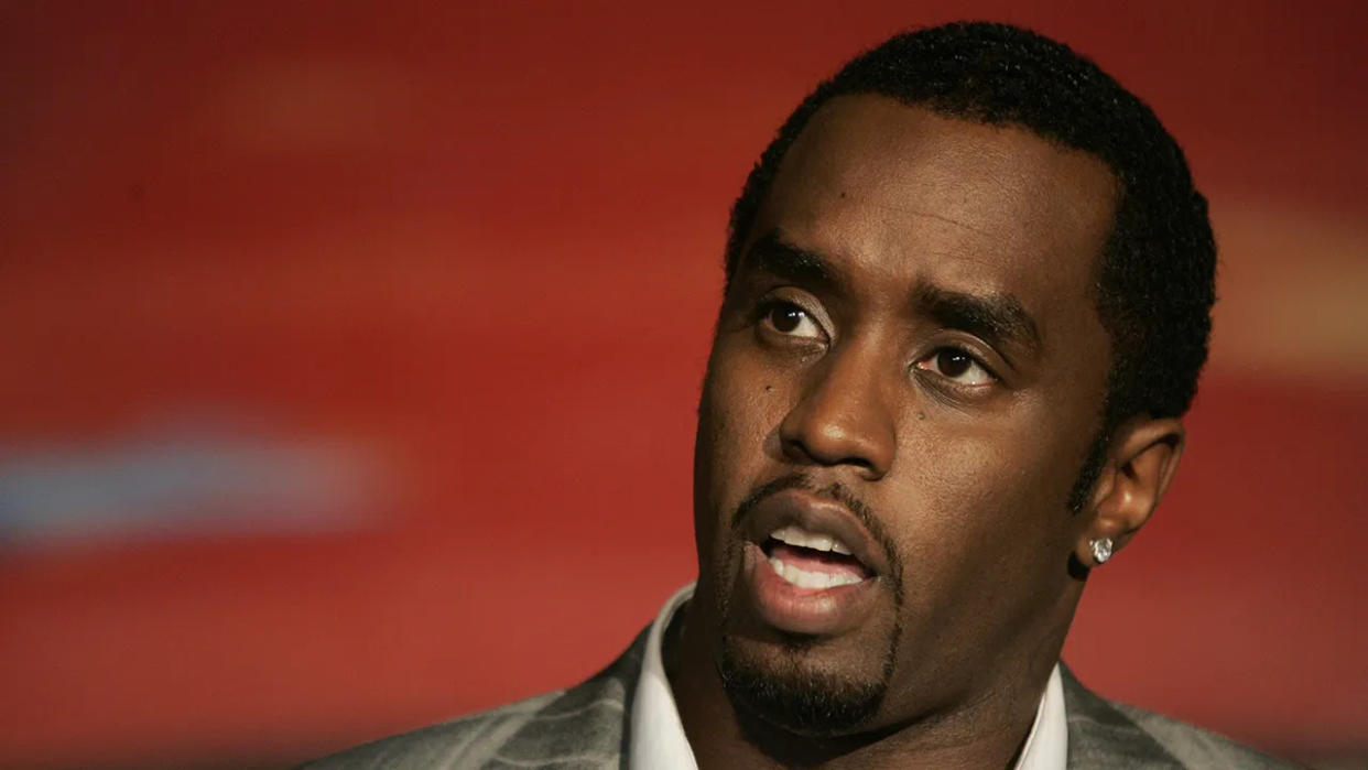 Sean Combs sits in front of red backdrop