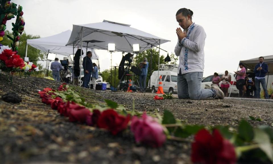 A person prays after placing roses on a makeshift memorial where the bodies were found.