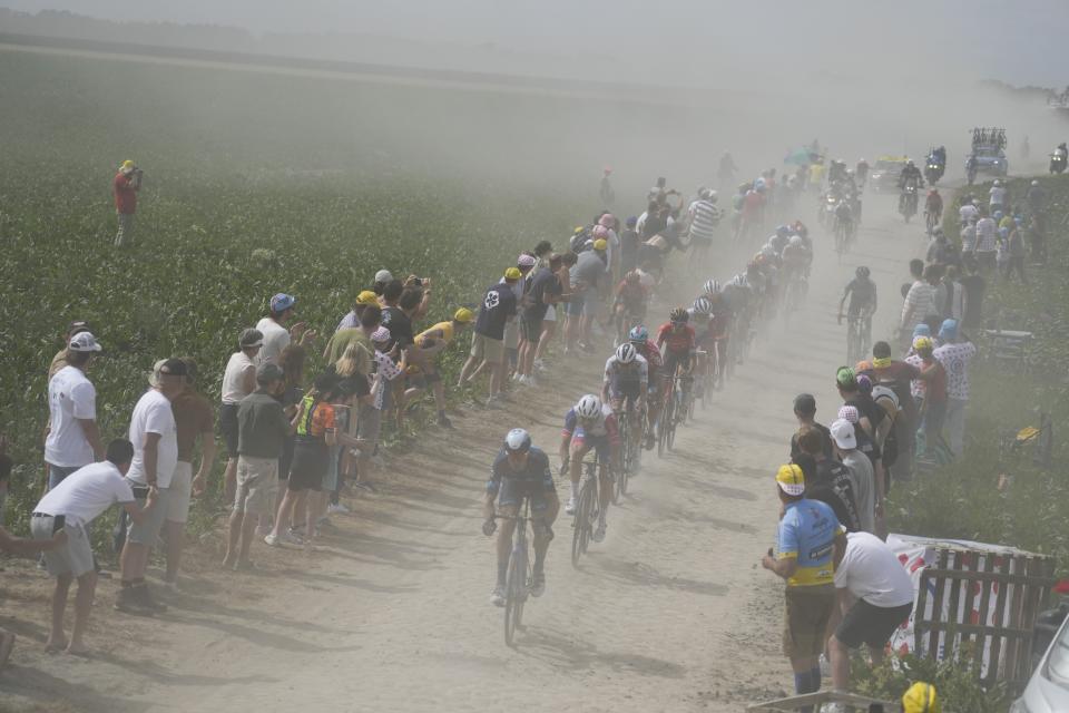 The pack kicks up dust as it rides over the cobblestones during the fifth stage of the Tour de France cycling race over 157 kilometers (97.6 miles) with start in Lille Metropole and finish in Arenberg Porte du Hainaut, France, Wednesday, July 6, 2022. (AP Photo/Thibault Camus)